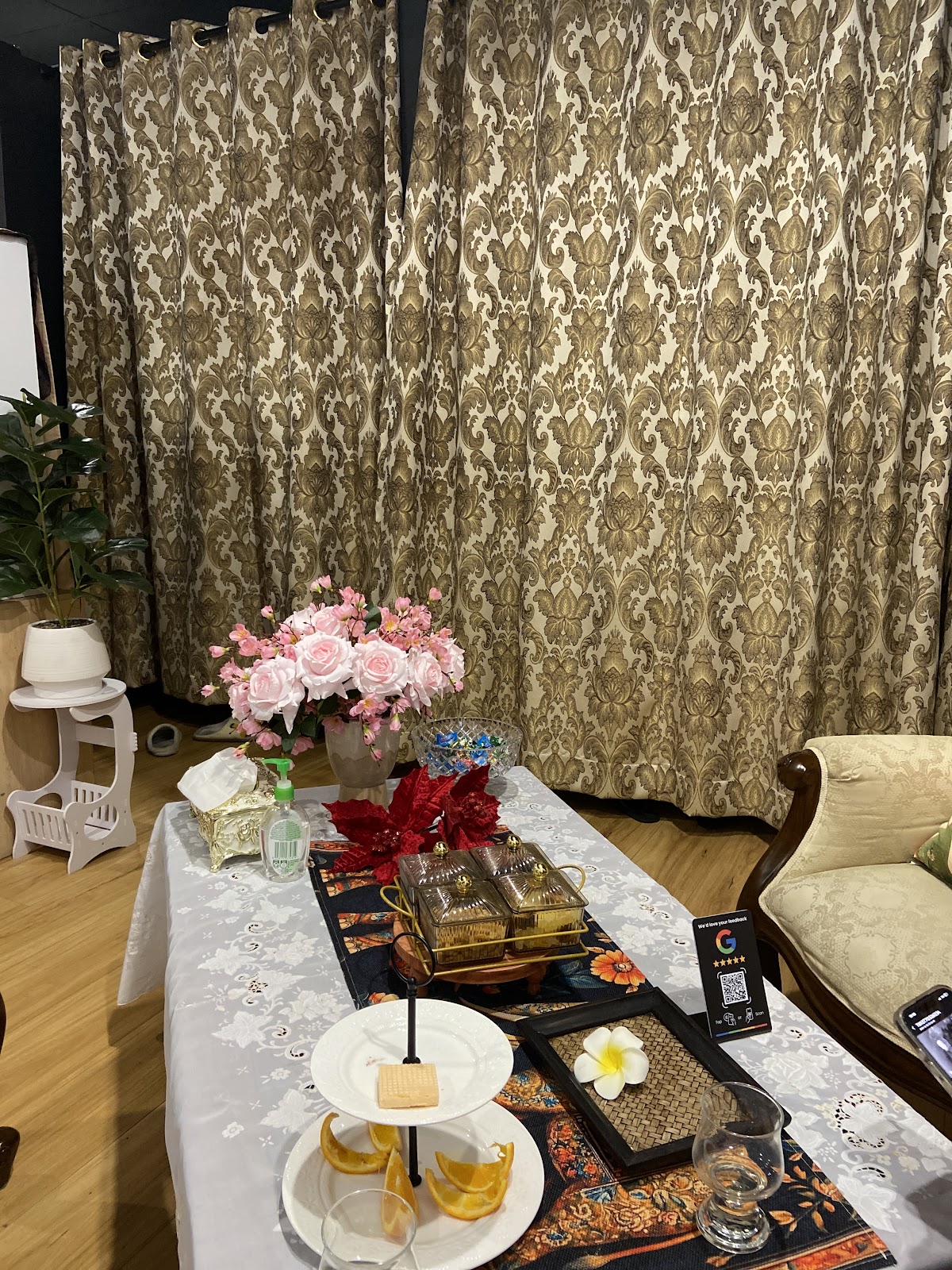 A curtained alcove with gold damask drapes and a small table