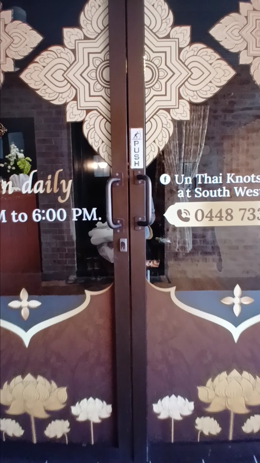 The front doors, painted with gold Thai patterns and the phone number