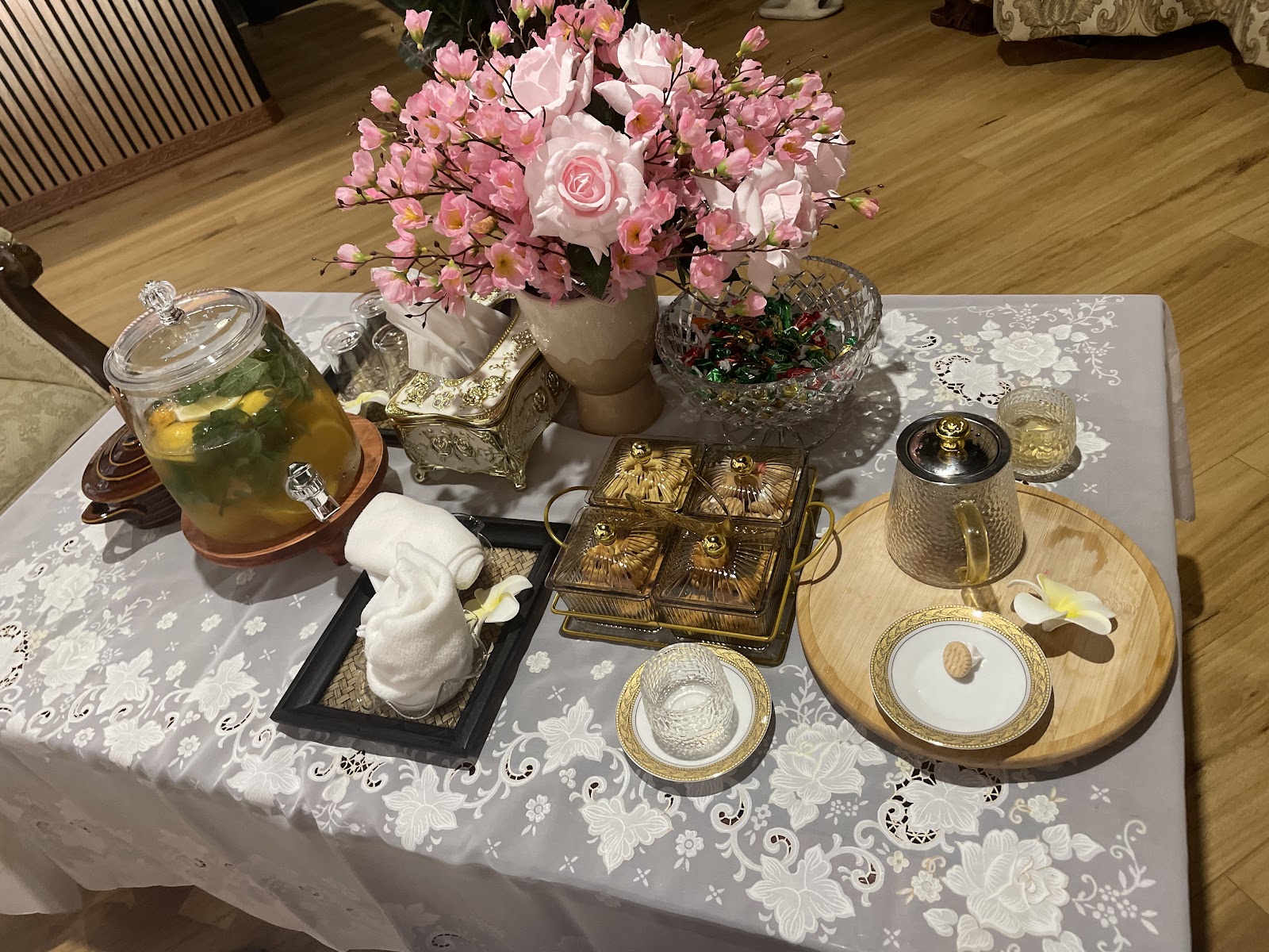 A table laid with herbal tea, small cakes and pink flowers