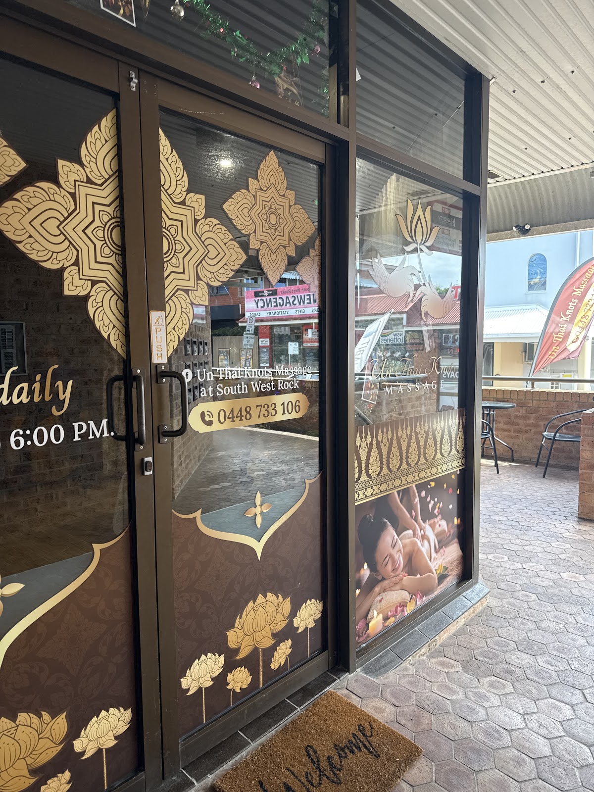 The gold patterned glass doors of Un Thai Knots Massage from the footpath